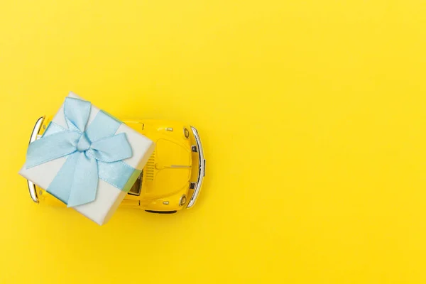 Einfach Design gelben Vintage-Retro-Spielzeugauto liefert Geschenkbox auf Dach isoliert auf trendigen gelben Hintergrund. Weihnachten Neujahr Geburtstag Valentinstag Feier präsentieren romantisches Konzept — Stockfoto