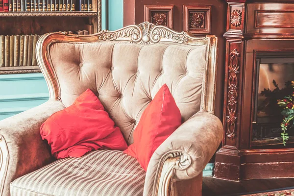 Ev kütüphanesinin lüks klasik iç. Kitaplık, kitap, kol koltuğu, kanepe ve şömineile oturma odası