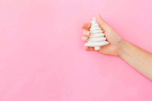Simplesmente design mínimo mulher feminina mão segurando Natal ornamento abeto isolado no pastel rosa colorido fundo da moda — Fotografia de Stock