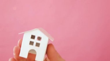 Sadece pembe pastel renkli trendy arka plan izole minyatür beyaz oyuncak ev tutan kadın kadın el tasarımı. Mortgage emlak sigortası rüya ev kavramı. Kopyalama alanı