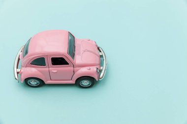 Pembe eski model oyuncak araba mavi pastel renkli arka planda izole edilmiş.