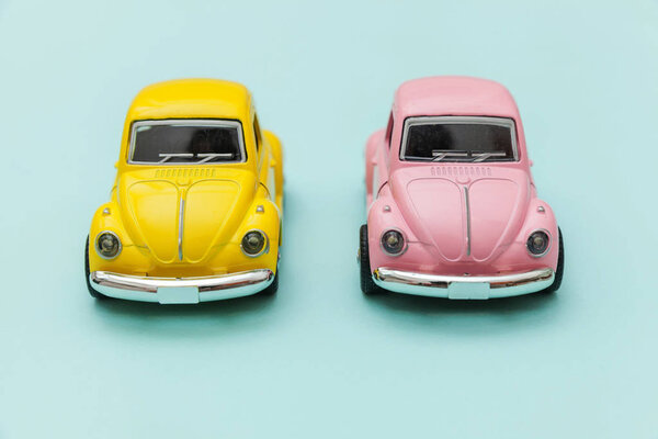 Просто дизайн с двумя желто-розовыми винтажными ретро-игрушками, изолированными на голубом цветовом фоне. Автомобильный и транспортный символ. Концепция доставки городского транспорта. Копирование текста
