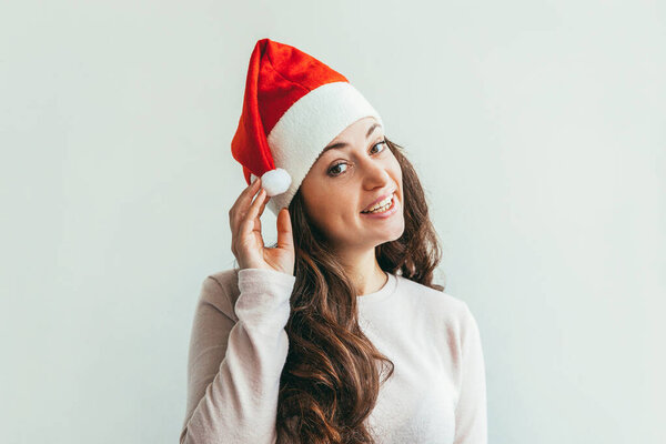 Beautiful girl with long hair in red Santa Claus hat isolated on white background looking happy and excited. Young woman portrait, true emotions. Happy Christmas and New Year holidays