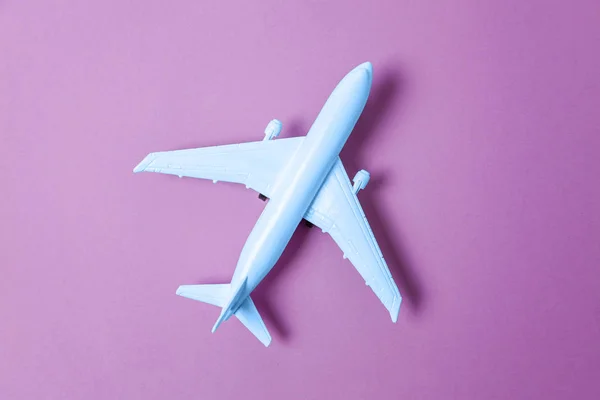 Plano de juguete de diseño simple y plano coloreado en color de moda del año 2020 Classic Blue sobre fondo violeta púrpura. Brillante Macro color 19-4052. Viaje en avión viaje viaje billete tour concepto —  Fotos de Stock