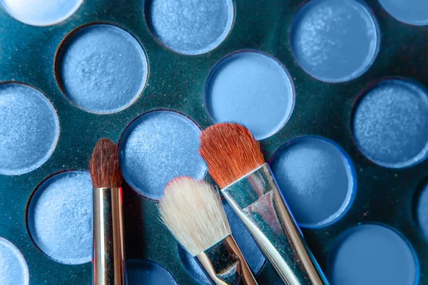 Herramientas para maquillaje y cosméticos diferentes tonos de sombra de ojos paleta de colores en el color de moda del año 2020 Classic Blue. Macro brillante usando el color 19-4052. Vista superior plana y pintoresca — Foto de Stock