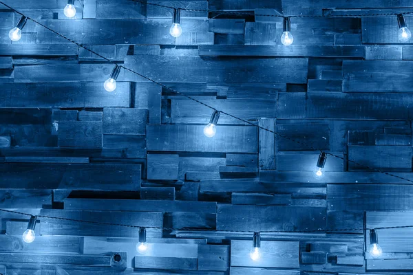 Moderno apartamento de diseño de interiores de estilo clásico con lámparas retro colgando bombillas de fondo de color en color de moda del año 2020 Classic Blue. Tablones de madera con lámparas —  Fotos de Stock