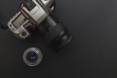 Karanlık masa arka planında DSR kamera sistemi ve lensleri olan fotoğrafçı işyeri. Hobi seyahat fotoğrafçılık konsepti. Düz görünüm kopyalama alanı.