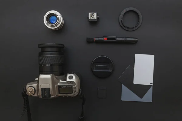 Lugar de trabajo del fotógrafo con sistema de cámara dslr, kit de limpieza de la cámara, lente y accesorio de la cámara sobre fondo de mesa negro oscuro. Hobby viaje fotografía concepto plano laico vista superior copia espacio —  Fotos de Stock