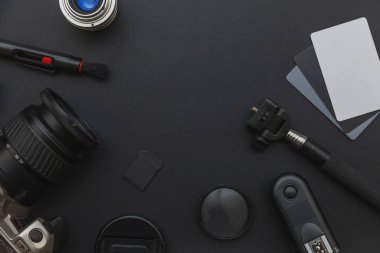 DSR kamera sistemi olan fotoğrafçı işyeri, kamera temizleme seti, siyah masa arka planında lens ve kamera aksesuarı. Hobi seyahat fotoğrafçılık konsepti. Düz görünüm kopyalama alanı.