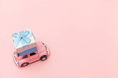 Pembe eski model oyuncak araba tasarımı. Moda pastel pembe arka planda izole edilmiş çatıda hediye kutusu dağıtımı. Noel, yeni yıl doğum günü Sevgililer Günü, hediye romantik konsept