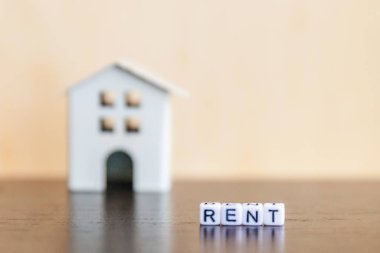 Minyatür oyuncak model ev kira harf kelime ahşap zemin üzerinde yazıt ile. Eko Köyü, çevre arka plan. Emlak mortgage Emlak sigorta tatlı ev ekoloji kira kavramı