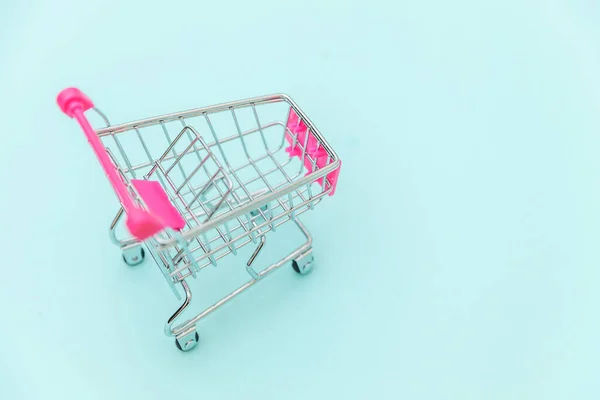 Pequeño supermercado carrito de compras empuje para juguete de compras con ruedas aisladas en azul pastel colorido fondo de moda Copiar el espacio. Venta comprar centro comercial tienda concepto de consumidor. —  Fotos de Stock