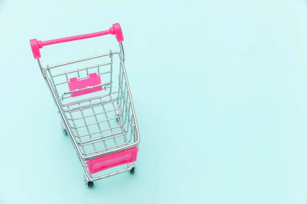 Petit supermarché épicerie poussette chariot pour jouet shopping avec roues isolées sur fond bleu pastel coloré tendance Copier l'espace. Vente acheter centre commercial marché boutique concept de consommateur. — Photo