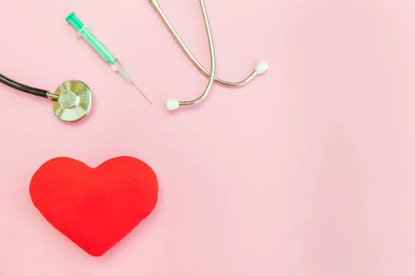 Equipamento de medicina estetoscópio ou seringa de fonendoscópio e coração vermelho isolado no moderno fundo rosa pastel — Fotografia de Stock