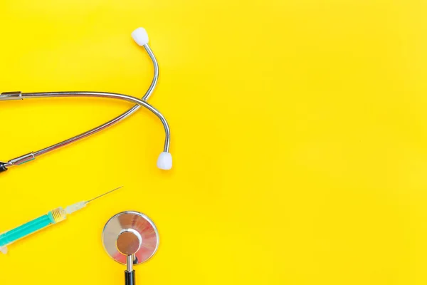 Equipamento de medicina estetoscópio ou fonendoscópio e seringa isolados em fundo amarelo moderno — Fotografia de Stock