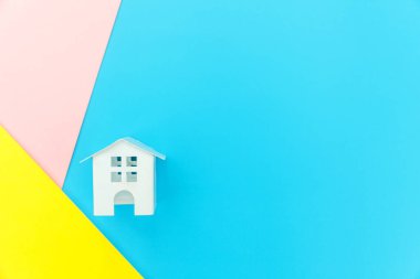 Mavi sarı pembe pastel renkli trendy geometrik arka planda izole minyatür beyaz oyuncak ev