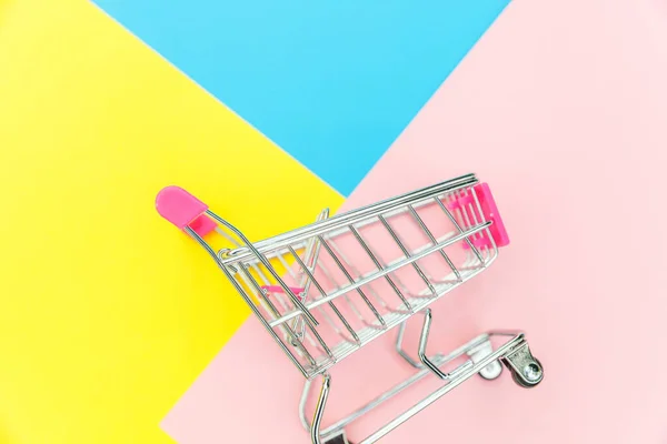 Kleiner Supermarkt Lebensmittelgeschäft Spielzeugwagen isoliert auf blau gelb und rosa pastellfarbenem Hintergrund — Stockfoto
