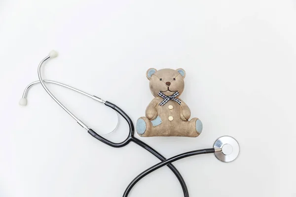 Simpelweg minimale ontwerp speelgoed beer en medische apparatuur stethoscoop geïsoleerd op witte achtergrond. Gezondheidszorg kinderen arts concept. Kinderarts symbool. Flat lay, bovenaanzicht kopieerruimte — Stockfoto