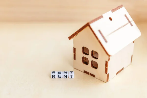 Miniaturní hračky modelu dům s nápisem Rent písmen slovo na dřevěné pozadí. Eco Village, abstraktní pozadí životního prostředí. Real estate hypoték vlastnosti pojištění sladké domácí ekologie nájemné koncept — Stock fotografie