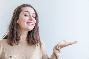 Neşeli gülümseyen mutlu kız. Güzel portre genç, mutlu, pozitif, gülen esmer kadın. Beyaz arka planda açık avuç içi gösteren ve gösteren. Ürün veya metin için alanı kopyala