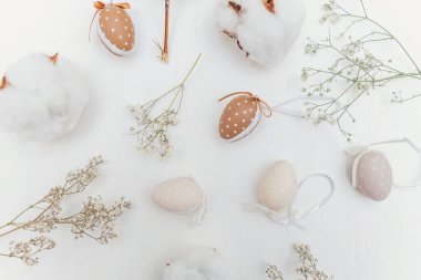 Kırsal beyaz ahşap arka planda yumurta, pamuk ve beyaz çiçeklerle Paskalya süslemesi