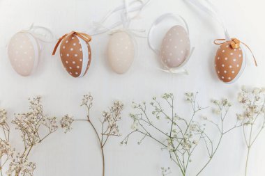 Kırsal beyaz ahşap arka planda yumurta, pamuk ve beyaz çiçeklerle Paskalya süslemesi