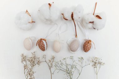 Kırsal beyaz ahşap arka planda yumurta, pamuk ve beyaz çiçeklerle Paskalya süslemesi