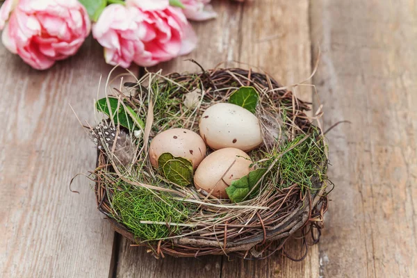 Ovos de Páscoa em ninho com musgo e rosa buquê de tulipa fresca no ru — Fotografia de Stock