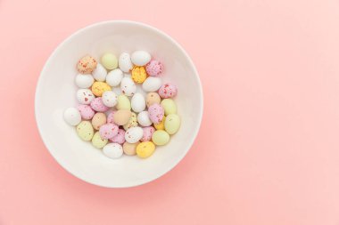 Mutlu Paskalya konsepti. Paskalya şekeri çikolata yumurta ve Jellybean tatlılar trendy pastel pembe arka planda izole. Basit minimalizm düz üst görünüm kopya alanı yatıyordu