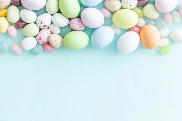 Happy Easter concept. Easter candy chocolate eggs and jellybean sweets isolated on trendy pastel blue background. Simple minimalism flat lay top view copy space — Stock Photo, Image