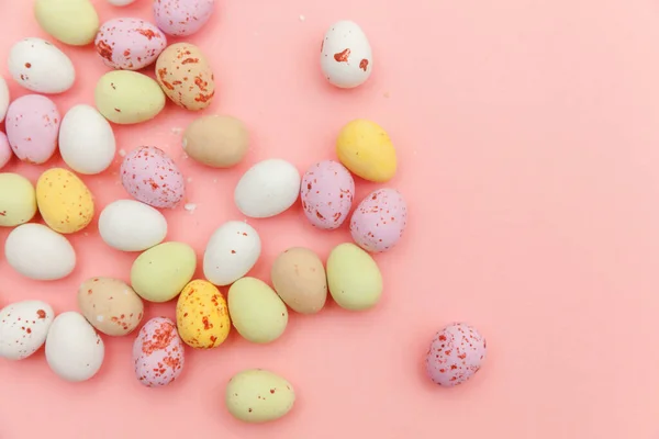 Feliz concepto de Pascua. Huevos de chocolate con caramelos de Pascua y dulces de gelatina aislados sobre un fondo rosa pastel de moda. Minimalismo simple plano laico vista superior copia espacio — Foto de Stock