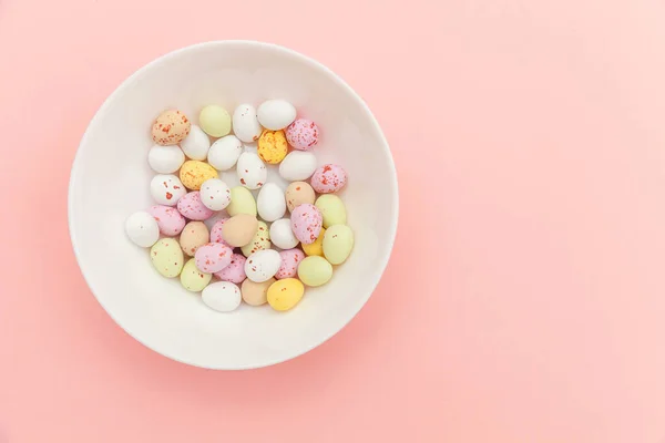 Feliz concepto de Pascua. Huevos de chocolate con caramelos de Pascua y dulces de gelatina aislados sobre un fondo rosa pastel de moda. Minimalismo simple plano laico vista superior copia espacio — Foto de Stock