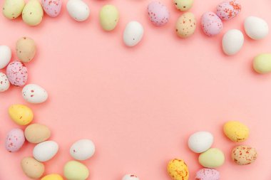 Mutlu Paskalya konsepti. Paskalya şekeri çikolata yumurta ve Jellybean tatlılar trendy pastel pembe arka planda izole. Basit minimalizm düz üst görünüm kopya alanı yatıyordu