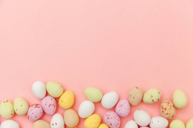 Mutlu Paskalya konsepti. Paskalya şekeri çikolata yumurta ve Jellybean tatlılar trendy pastel pembe arka planda izole. Basit minimalizm düz üst görünüm kopya alanı yatıyordu
