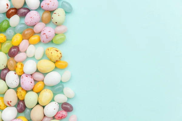 Feliz concepto de Pascua. Preparación para las vacaciones. Huevos de chocolate con caramelos de Pascua y dulces de gelatina aislados sobre un fondo azul pastel de moda. Minimalismo simple plano laico vista superior copia espacio. — Foto de Stock