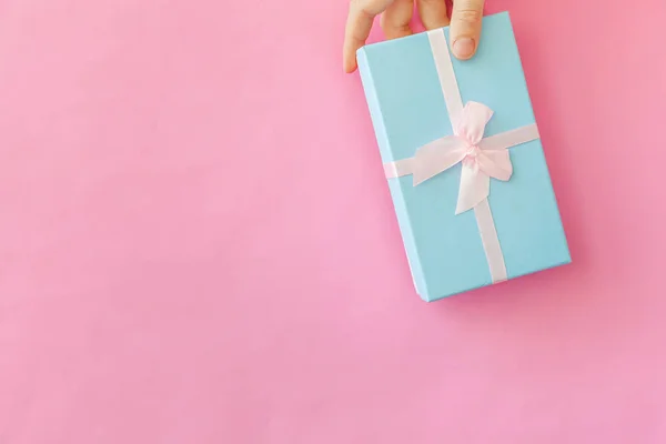 Simplemente diseñe la mano femenina de la mujer que sostiene la caja de regalo azul aislada en un fondo de moda colorido pastel rosa. Navidad Año Nuevo cumpleaños celebración de San Valentín presente concepto romántico. Copiar espacio. —  Fotos de Stock