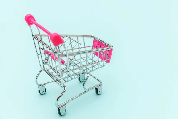 Kleine supermarkt kruidenierswinkelwagentje om te winkelen speelgoed met wielen geïsoleerd op blauw pastel kleurrijke trendy achtergrond Kopieer ruimte. Verkoop kopen winkelcentrum winkel consument concept. — Stockfoto
