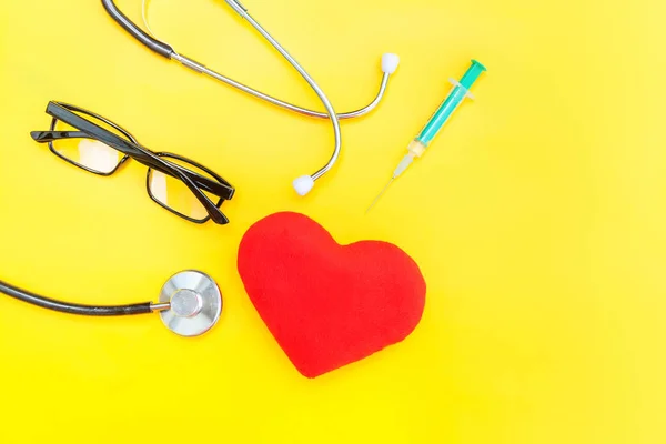 Equipamento de medicina estetoscópio ou óculos de fonendoscópio seringa e coração vermelho isolado no fundo amarelo na moda — Fotografia de Stock