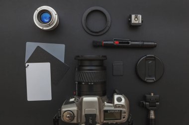 DSR kamera sistemi olan fotoğrafçı işyeri, kamera temizleme seti, siyah masa arka planında lens ve kamera aksesuarı. Hobi seyahat fotoğrafçılık konsepti. Düz görünüm kopyalama alanı.