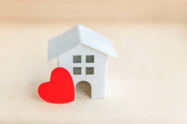 Ahşap zemin üzerinde kırmızı kalbi olan minyatür oyuncak model ev. Eco Village soyut çevre geçmişi. Gayrimenkul ipoteği sigortası tatlı rüya ev ekolojisi kavramı