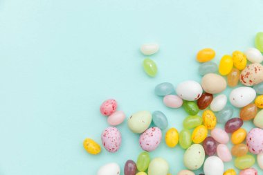Mutlu Paskalyalar. Tatil için hazırlık. Paskalya çikolatalı yumurtalar ve jöleli şekerler modayı takip eden mavi arka planda izole edilmiş. Basit minimalizm düz üst görünüm kopyalama alanı.