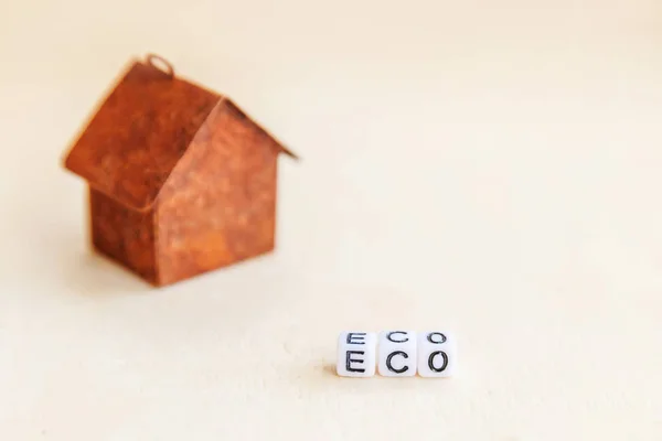 Miniatuur speelgoed modelhuis met inscriptie Eco letters woord op houten achtergrond. Eco Village, abstracte milieu-achtergrond. Ecologie nul afval sociale verantwoordelijkheid recyclen bio home concept — Stockfoto