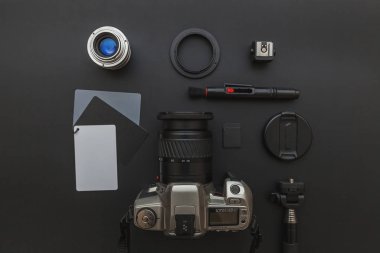 DSR kamera sistemi olan fotoğrafçı işyeri, kamera temizleme seti, siyah masa arka planında lens ve kamera aksesuarı. Hobi seyahat fotoğrafçılık konsepti. Düz görünüm kopyalama alanı.