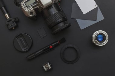 DSR kamera sistemi olan fotoğrafçı işyeri, kamera temizleme seti, siyah masa arka planında lens ve kamera aksesuarı. Hobi seyahat fotoğrafçılık konsepti. Düz görünüm kopyalama alanı.