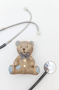 Minimum tasarım oyuncak ayı ve tıbbi ekipman steteskopu beyaz arka planda izole edilmiş. Sağlık hizmetleri çocuk doktoru konsepti. Çocuk doktoru sembolü. Düz konum, üst görünüm kopyalama alanı