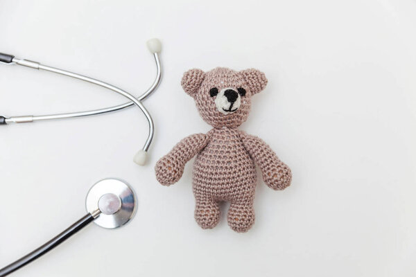 Simply minimal design toy bear and medicine equipment stethoscope isolated on white background. Health care children doctor concept. Pediatrician symbol. Flat lay, top view copy space