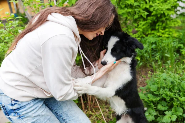 Glimlachend jong aantrekkelijk vrouw omarmen huging cute puppy hond Border Collie in zomer stadspark buiten achtergrond — Stockfoto