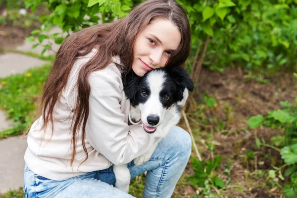 Glimlachend jong aantrekkelijk vrouw omarmen huging cute puppy hond Border Collie in zomer stadspark buiten achtergrond — Stockfoto