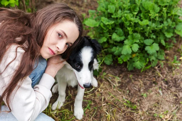 Sonriendo joven atractiva mujer abrazando abrazo lindo cachorro perro frontera collie en verano ciudad parque al aire libre fondo — Foto de Stock