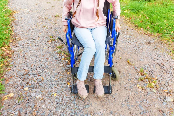 Piernas pies hándicap mujer en silla de ruedas en la carretera en el parque del hospital a la espera de los servicios al paciente. Chica paralítica irreconocible en silla inválida para personas con discapacidad al aire libre. Concepto de rehabilitación . — Foto de Stock